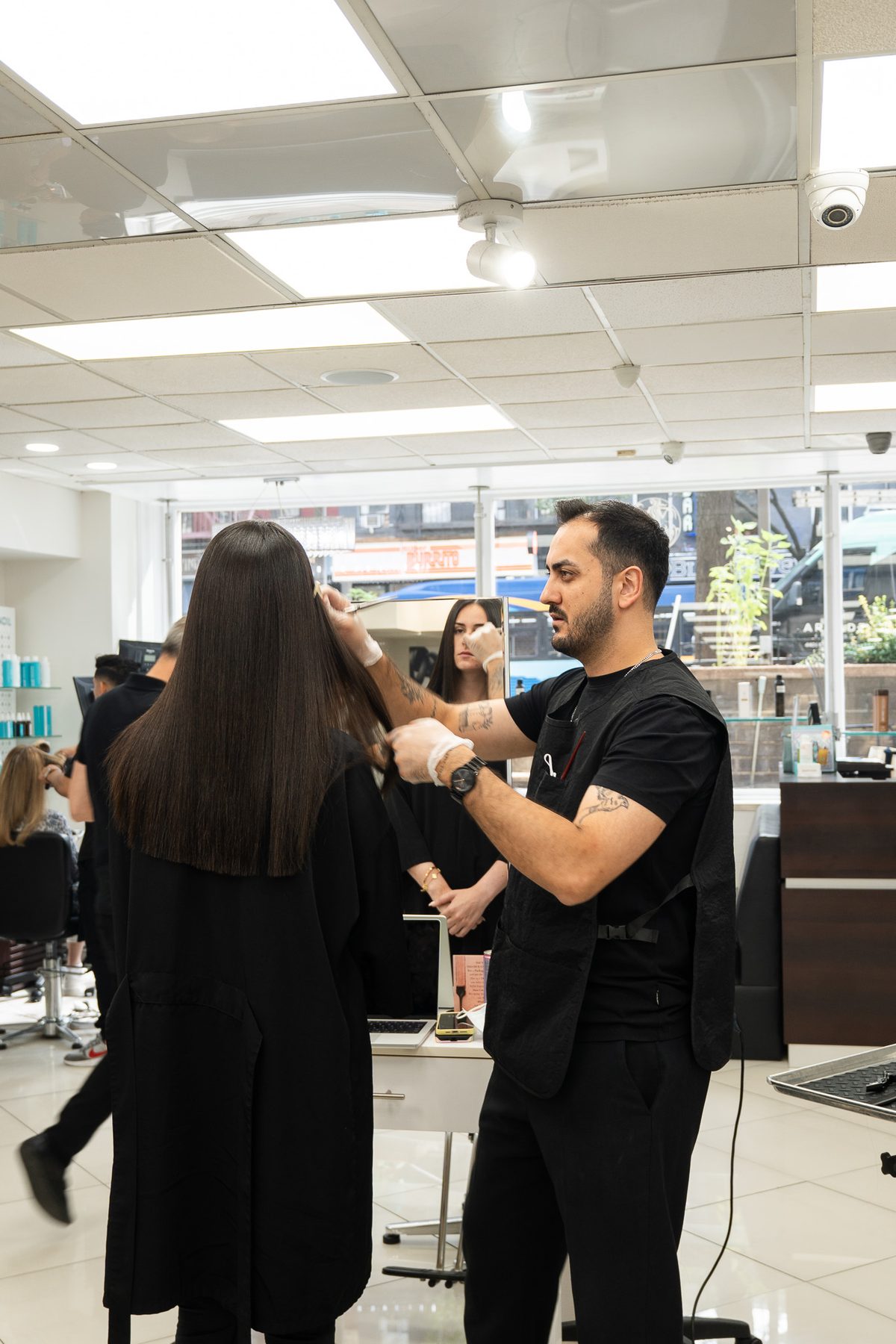 Stylist cutting hair in front of the mirror at Salon Icon NYC